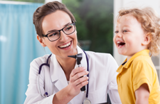 A physician examining a smiling toddler