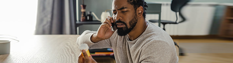 Man on phone looking at pills