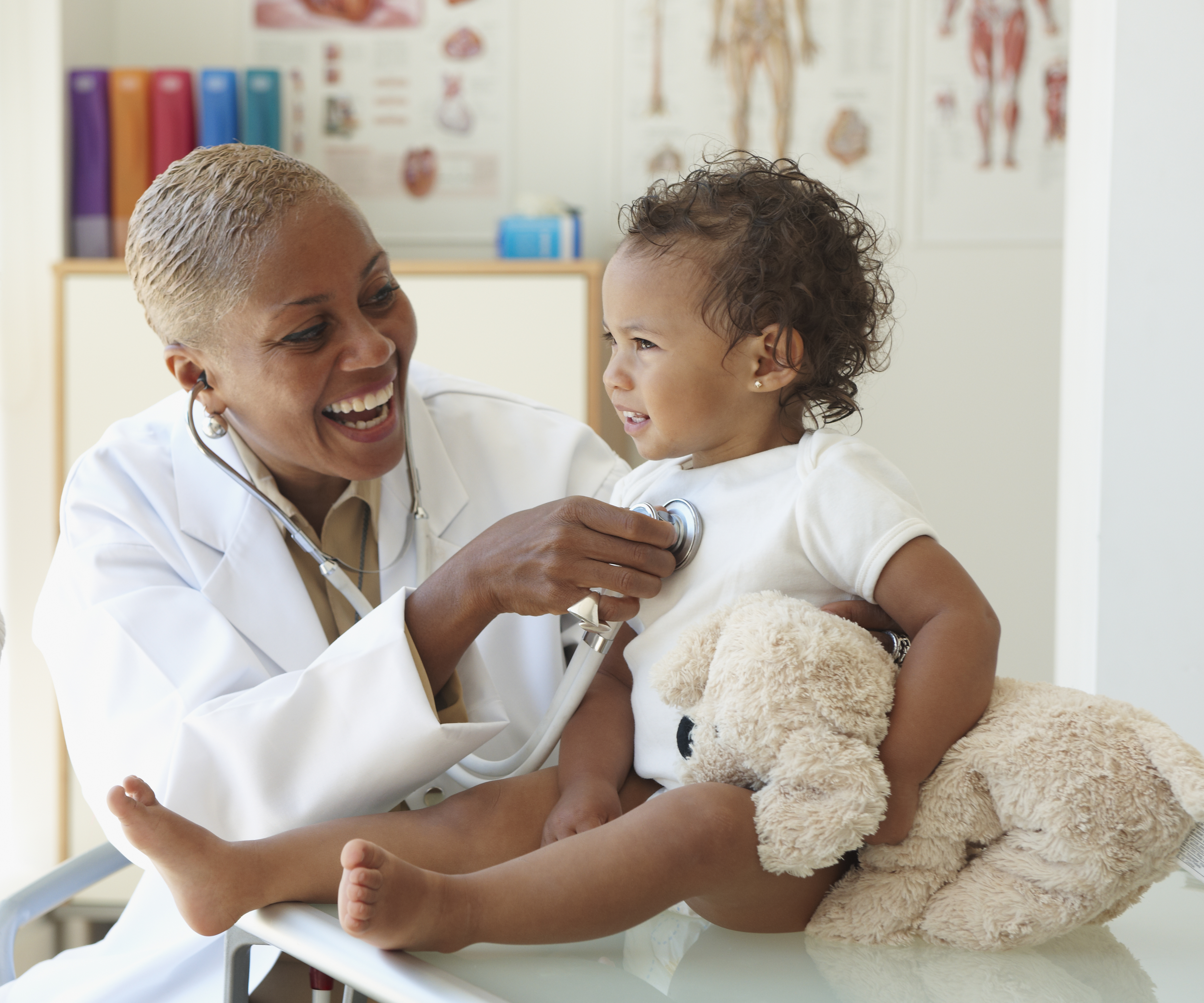 Baby smiling at doctor listening to her chest